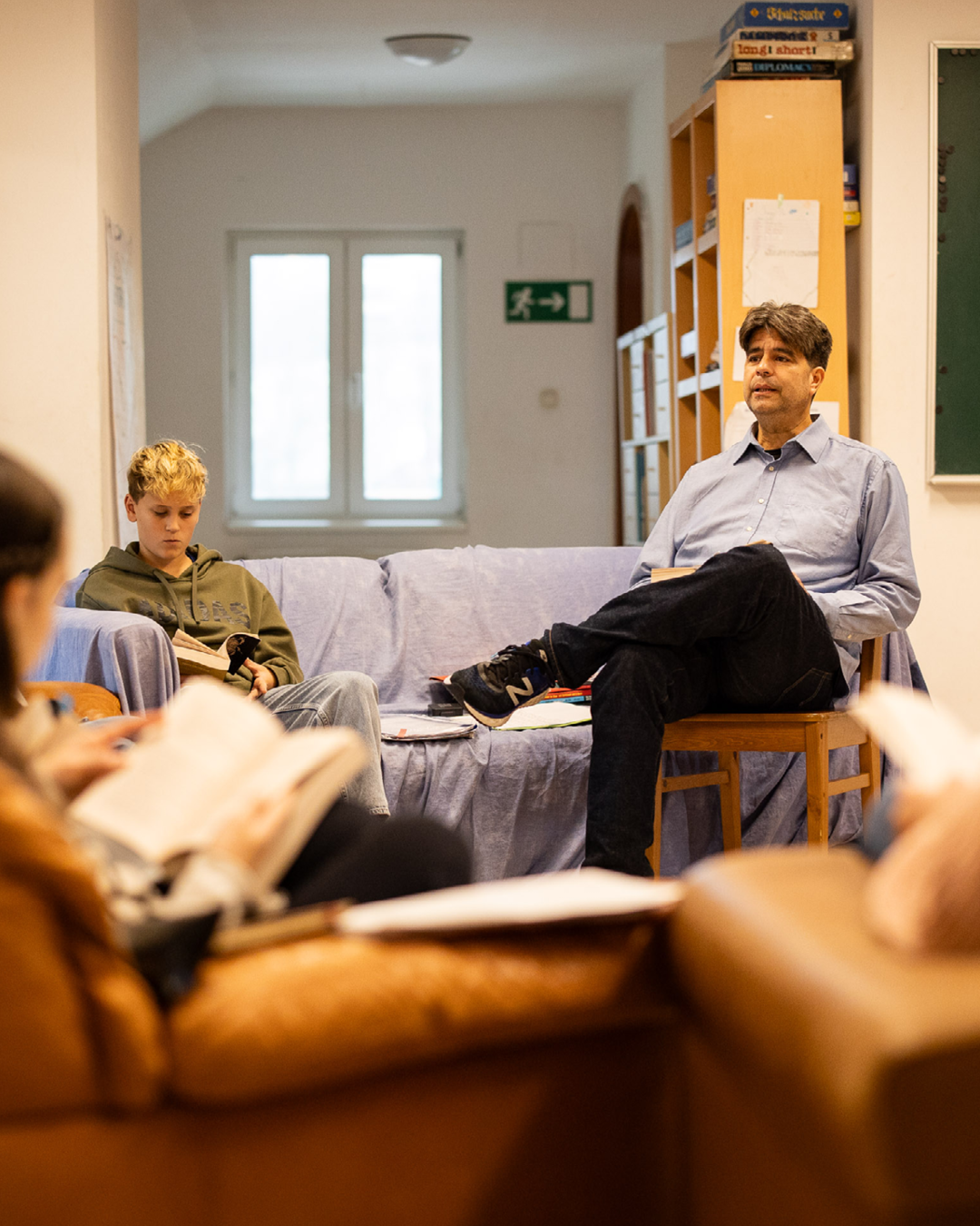 Zwei Personen lesen in einem Lernraum: rechts sitzt eine Person auf einem Stuhl und liest, links auf dem Sofa eine Person mit Hoodie liest.