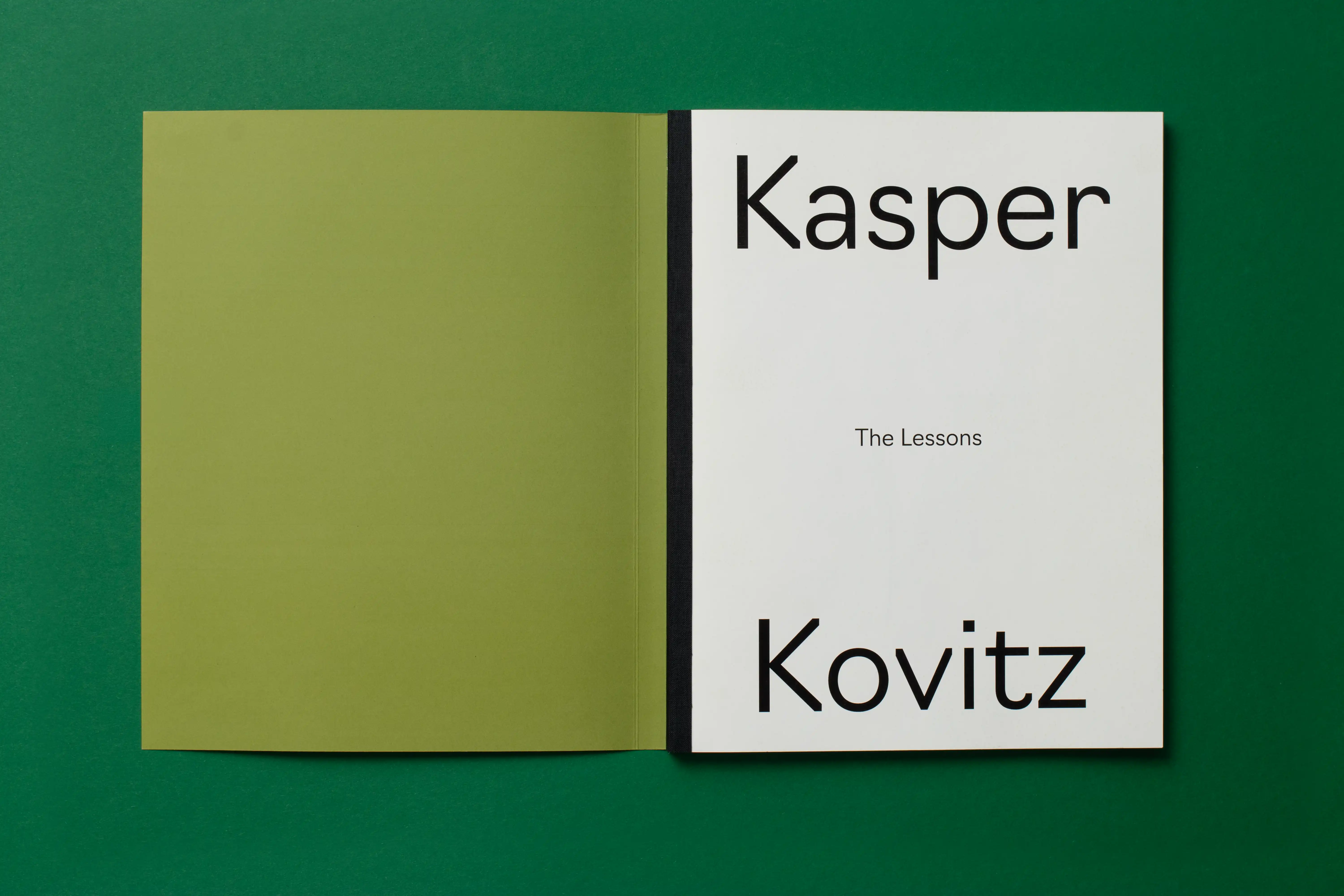 Open book on green surface; white title page reads Kasper Kovitz with subtitle The Lessons.