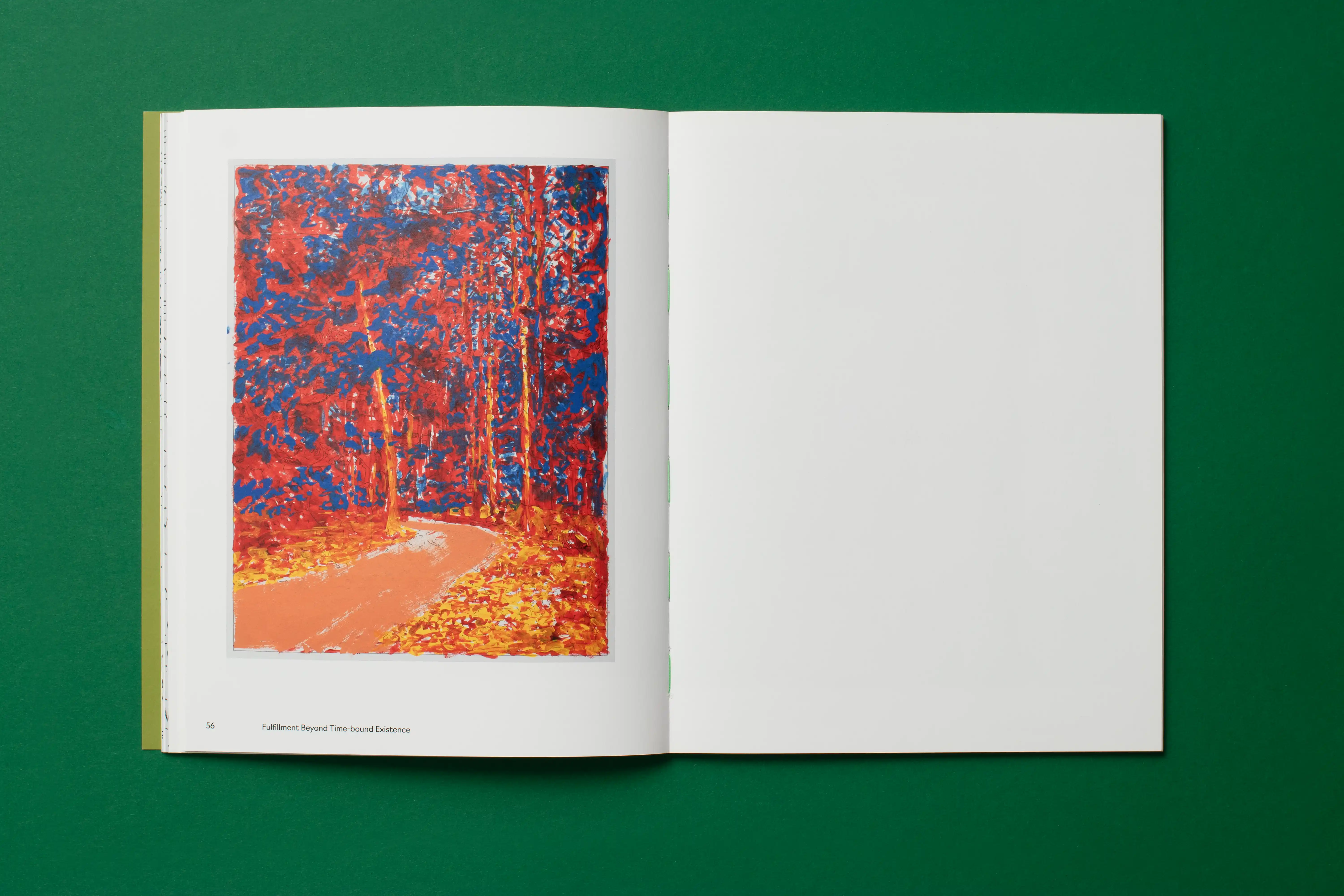 Open book on a green surface; left page shows an autumn forest path painting, right page is blank.